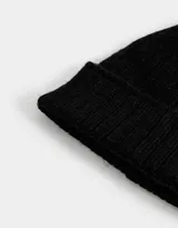 Gorro de lana tejido color negro con pompón de piel sintética en la parte superior y borde acanalado.