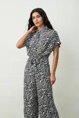 Mono largo negro de corte palazzo con camisa de mangas cortas con botones y lazo en la cintura.