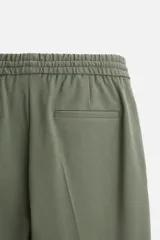 Pantalón color arena de corte recto, confeccionado en tejido elástico. Cuenta con cintura elástica ajustable con cordón, bolsillos laterales y bolsillos de vivo en la parte trasera.