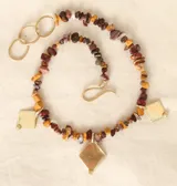 Collar corto de piedras irregulares en tonos borgoña, amarillo y marrón, con dijes de bronce en forma de rombo.