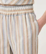 Conjunto de pantalón y blusa de algodón a rayas verticales en tonos beige, celeste y blanco. El pantalón es de corte recto con cintura elástica y puños ajustados. La blusa es de corte crop con escote en V y mangas cortas abullonadas.