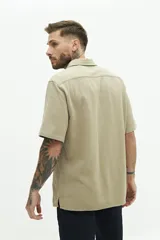 Camisa de manga corta color beige, con textura tipo crepé y cuello camisero.