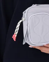Bandolera celeste de tela deportiva acolchada con doble bolsillo con cierre, correa regulable y desmontable, manija superior, cierre superior y tag de metal.