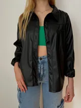 Sobrecamisa oversize de ecocuero color negro, con bolsillo delantero y puños ajustables.
