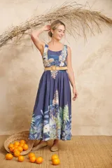 Vestido midi azul con estampado de palmeras y otros motivos tropicales, escote redondo y cinto de rafia.
