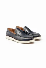 Mocasines color marrón de cuero con antifaz y suela de goma blanca.