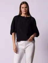 Blusa blanca de gasa marca Sioni, con cuello a la base y escote en V con botones.