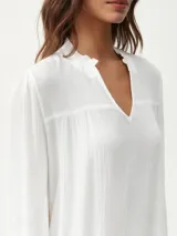 Blusa blanca de manga larga con escote en V y textura arrugada.