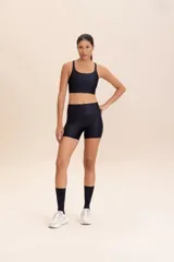 Top negro de tirantes finos y cruzados, con relleno extraíble y superficie acanalada, diseñado para adaptarse al cuerpo.