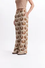Pantalón wide leg estampado con diseño de conchas marinas color marrón sobre fondo blanco.