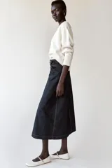 Falda midi de denim azul oscuro, de tiro alto, con diseño cruzado, abertura frontal y ajuste lateral con doble hebilla metálica.