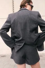 Short pollera gris oscuro con estampado a cuadros (Príncipe de Gales o similar), de corte acampanado con pliegues en el frente.