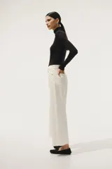 Pantalón jean blanco de corte ancho, tiro alto y largo tobillero. Confeccionado en denim de algodón levemente elástico, con cinco bolsillos, cierre frontal con botón y pierna amplia.