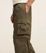 Pantalón paper touch color verde militar, con bolsillos laterales, cintura elástica y cordón de ajuste. Se convierte en bermuda gracias a un cierre a la altura de la rodilla.