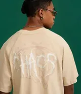 Remera de algodón color beige claro, corte boxy, con cuello redondo y mangas cortas. Presenta un estampado frontal en blanco con la palabra "Chaos" en tipografía estilizada.