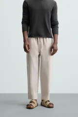 Pantalón negro de lino, corte recto y relaxed fit, con cintura elástica ajustable con cordón, bolsillos laterales y traseros.