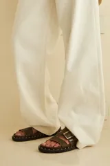Sandalias de cuero color marrón con tachas en la suela y ajuste de hebilla en el empeine.