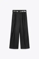 Pantalón negro de tiro alto con pinzas delanteras, pernera ancha y cinturón de cuero con hebilla dorada.