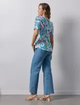Remera estampada con diseño paisley en tonos celeste, rosa, amarillo y verde. Tiene mangas cortas con detalle de aberturas y lazos en los hombros.