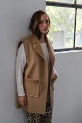 Chaleco largo color beige, con solapas y bolsillos delanteros con borde de corderito.