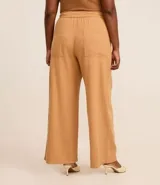 Pantalón pantalona color beige, de tiro alto, con cintura fija, trabillas, cierre tradicional, bolsillos, elástico trasero y cinturón con hebilla redonda.