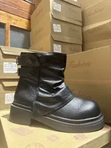 Botas cortas negras de cuero sintético con diseño arrugado en el empeine, tira ancha cruzada y hebillas laterales. Suela track con plataforma.