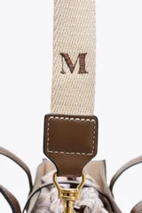 Bolso tipo shopper color marrón con doble asa corta y correa larga extraíble. Tiene detalle de pespuntes y anilla metálica decorativa. Incluye bolsa de tela interior extraíble con cierre fruncido.
