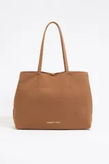 Bolso shopper Chihuahua de Bimba y Lola, formato horizontal, color marrón, con doble asa de tejido, piezas de piel y logo metálico. Presenta cierre de mosquetón, bolsillo interior con cremallera e interior con placa metálica logotipada.