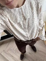 Pantalón de pana color marrón, de corte mom fit, con tiro alto y bolsillos delanteros y traseros. Se ajusta a la cintura con cinturón de cuero marrón.