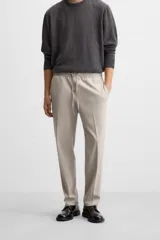 Pantalón color arena de corte recto, confeccionado en tejido elástico. Cuenta con cintura elástica ajustable con cordón, bolsillos laterales y bolsillos de vivo en la parte trasera.