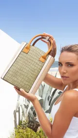 Matera combinada en símil cuero color verde y beige, con textura croco. Tiene división interior, asas cortas de mano y broche en el asa.