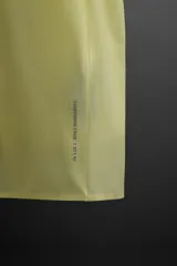 Camiseta deportiva color amarillo claro confeccionada en tejido técnico ligero y elástico. Cuenta con cuello redondo, manga corta, costuras termofijadas y estampaciones reflectantes en la espalda.