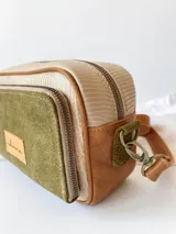 Bandolera rectangular de cuero color beige con frente de gamuza verde oliva y detalles en cuero marrón. Tiene correa larga de cuero marrón regulable y cierre superior con cremallera.