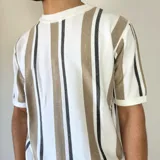 Remera tejida de manga corta con cuello redondo y diseño a rayas verticales en tonos blanco, gris y negro.