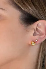 Par de aros dorados, uno con forma de nudo y otro con piedra de la luna y zirconia engarzada.