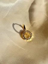 Arito dorado con forma circular, centro negro y strass blancos alrededor. Se vende por unidad.