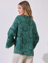 Blusa de satén estampada en tonos azules, con escote en V y lazo, y mangas largas con volados.