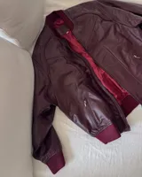 Campera bomber de cuero color bordó con forro interior rojo, cuello, puños y cintura acanalados.