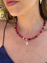 Gargantilla de cuentas blancas con dije de estrella de mar dorada.