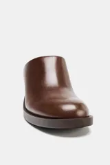 Zueco de cuero marrón con tacón de madera y punta redonda.