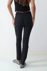 Pantalón recto cropped negro de tiro medio y fit slim, confeccionado en tejido elasticado. No tiene bolsillos visibles y cuenta con cierre frontal oculto.