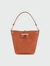 Bolso Longchamp modelo Le Roseau XS, color beige, tipo bucket bag, con correa larga ajustable para usar como bandolera.