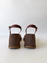 Sandalias de cuero con plataforma, color marrón con tira dorada sobre los dedos y tobillera marrón con hebilla.