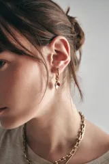 Aros dorados tipo argolla con dije de corazón en metal y piedras facetadas rojas.