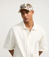 Gorra de sarga con estampado animal print de vaca, modelo dad hat con visera curva y ajuste trasero. Confeccionada en algodón sostenible.