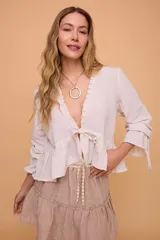 Blusa color crema con escote en V, mangas largas con volados y lazo delantero.