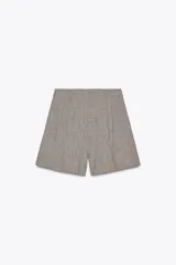 Bermuda color gris con estampado a cuadros, de tiro alto con pinzas delanteras, bolsillos frontales y falsos bolsillos con solapa en la espalda.