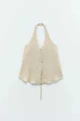 Top color beige claro, sin mangas, con tiras finas hacia el cuello y espalda descubierta que se cierra con dos lazos ajustables.
