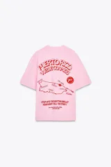 Camiseta rosa de algodón con efecto lavado, corte regular, cuello redondo y mangas cortas. Estampado frontal con la frase "Puerto Rico Vuela Conmigo".