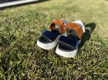 Sandalias con plataforma blanca y tiras de cuero en color negro, blanco y marrón. Las tiras tienen diferentes texturas: cuero liso, cuero con textura de cocodrilo y gamuza.